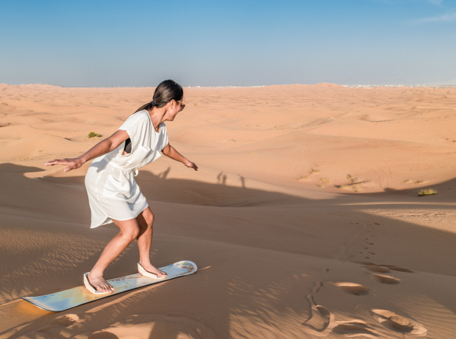 Visitor experiences sandboarding in the sand dunes 